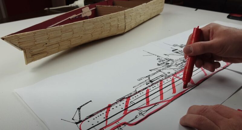 Artist marking the lines of a matchsticks ship model