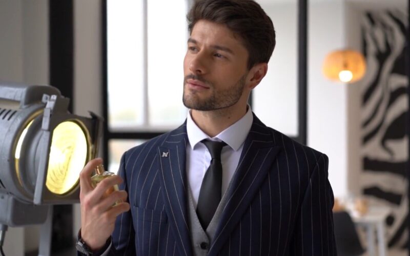 A man in a pinstriped suit, applying cologne, exudes confidence and style