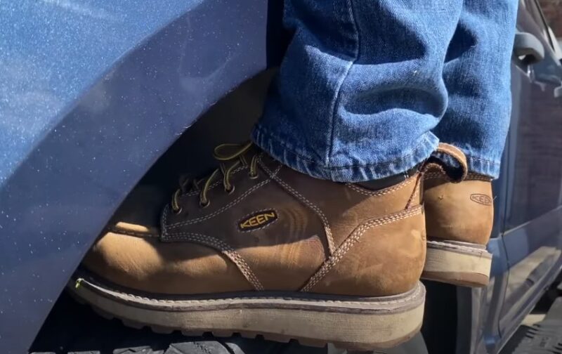 Driver standing on a truck tire, wearing boots